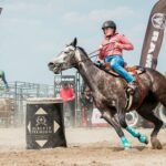 woman saddle bronc riding during rodeo event