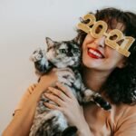 cheerful woman in decorative glasses embracing cute cat