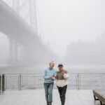 content couple talking on urban embankment against river in mist
