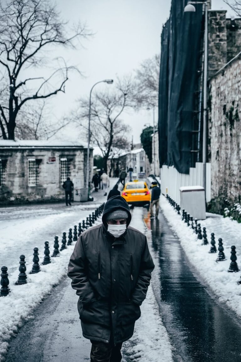 man in medical mask walking on snowy crowded street