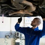 man in blue coverall fixing a vehicle